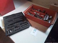 Overview of red tray with loose sockets and black socket set case