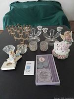 Full lot showing metal candelabrum, glass candlesticks, cut glass votives, cherub holders, angel figurine, boxed candles