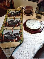 Loon banner, ceramic pot, wooden wall clock, brass candle holder displayed on table