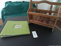 Wooden magazine rack beside green hardcover photo album