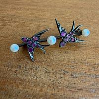 Front view of brooch showing birds with pink stones and three pearls