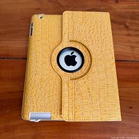 Rear view of iPad inside yellow rotating faux-alligator case showing Apple logo cut-out