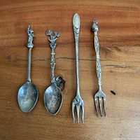 Four assorted vintage spoons and forks on wood surface