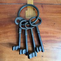 Four cast iron keys on ring laid on wooden surface