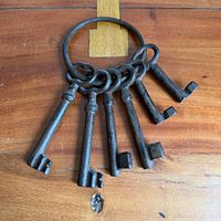 Six cast iron keys attached to a ring displayed on wooden surface