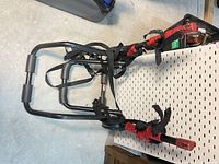 Full view of folded trunk-mount bike rack showing frame and red cradles