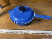 Full view of blue saucepan with lid, ruler for scale