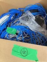 open box filled with blue and white Cat5e cables, RJ45 ends visible