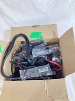 Open box filled with multiple black ATX power cables in plastic sleeves