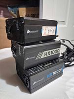 Three Corsair HX series 1000W power supplies stacked showing front and side panels