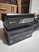 Corsair HX1200 stacked on Thermaltake RGB1200W showing branding