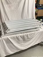 Stacked white steel adjustable window bars showing overall quantity