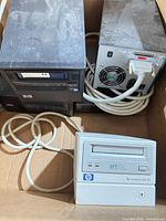 Box containing two black HP external tape drives, one beige internal drive, SCSI cables