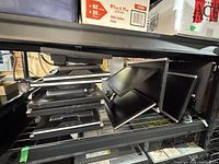 Stack of multiple black monitors on shelving unit