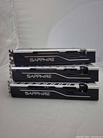Three Sapphire RX 570 cards stacked side view showing Sapphire logo and cooler shroud