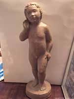 Front view of child figure sculpture with hand to ear