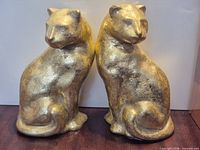 Front view of both gold-tone cat figurines