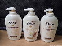 Front view of three Dove Caring Hand Wash bottles