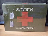 Front view of sealed M*A*S*H Complete Collection box showing shrink wrap, dog tags, red cross, bilingual title
