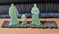 Front view of three green translucent Jedi spirit figurines on brown plank-style base