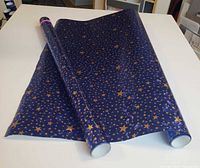 Two full rolls of blue paper with gold stars on table