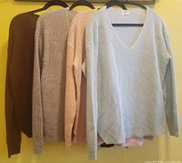 Front view of all four sweaters on hangers showing colors and style