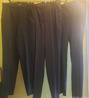 Three pairs of dark women’s pants hanging on rack