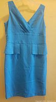 Full front view of sleeveless turquoise dress on hanger