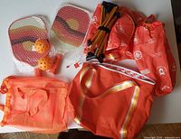 Overview of paddles in bubble wrap, balls, folded chair frame, seat fabric, mesh and shoulder bags