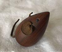 Left side view of teak mouse showing ears, tail, eyes, wood grain