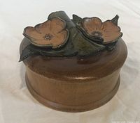 closed round wooden trinket box with floral leather lid
