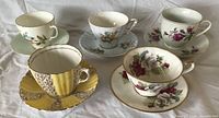 Five assorted bone china teacup and saucer sets displayed together