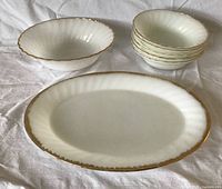 Overall view showing oval platter, large bowl, five small bowls, white milk glass with gold rims