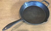 Top view of cast iron skillet showing interior surface, long handle, helper handle and pour spouts