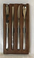 Wood tray with four stainless utensils inserted