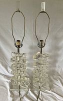 Front view of both clear Lucite lamps showing stacked block design, bases, harps, finials, and cords