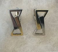 Front view of both cufflinks showing geometric open-frame design and silver-tone finish