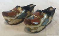 Oblique view of both ceramic clogs showing painted floral design
