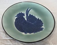 Front view of plate showing celadon glaze and blue rooster motif