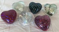 six heart-shaped glass paperweights grouped on cloth