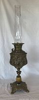 Full view of ornate brass oil lamp with glass chimney