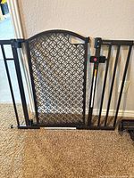 Black metal walk-through gate showing full front view with latch and lattice panel