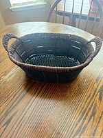 Top angled view showing entire dark brown woven basket with handles