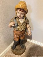 Full view of ceramic boy fisherman statue on round base