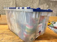 Clear plastic storage tub with blue lid filled with holiday items