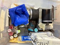 Plastic bin containing rock tumbler, grit jars, gloves and supplies