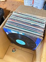 Box of stacked 12-inch LP records with one record partially visible
