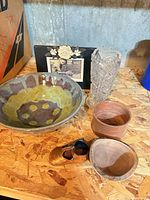 Overview of all items: pottery bowl, two wooden bowls, crystal vase, photo frame, brass clog