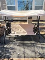 Front view of patio swing showing metal frame, seat, and canopy