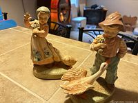 Both child-and-geese porcelain figurines side by side